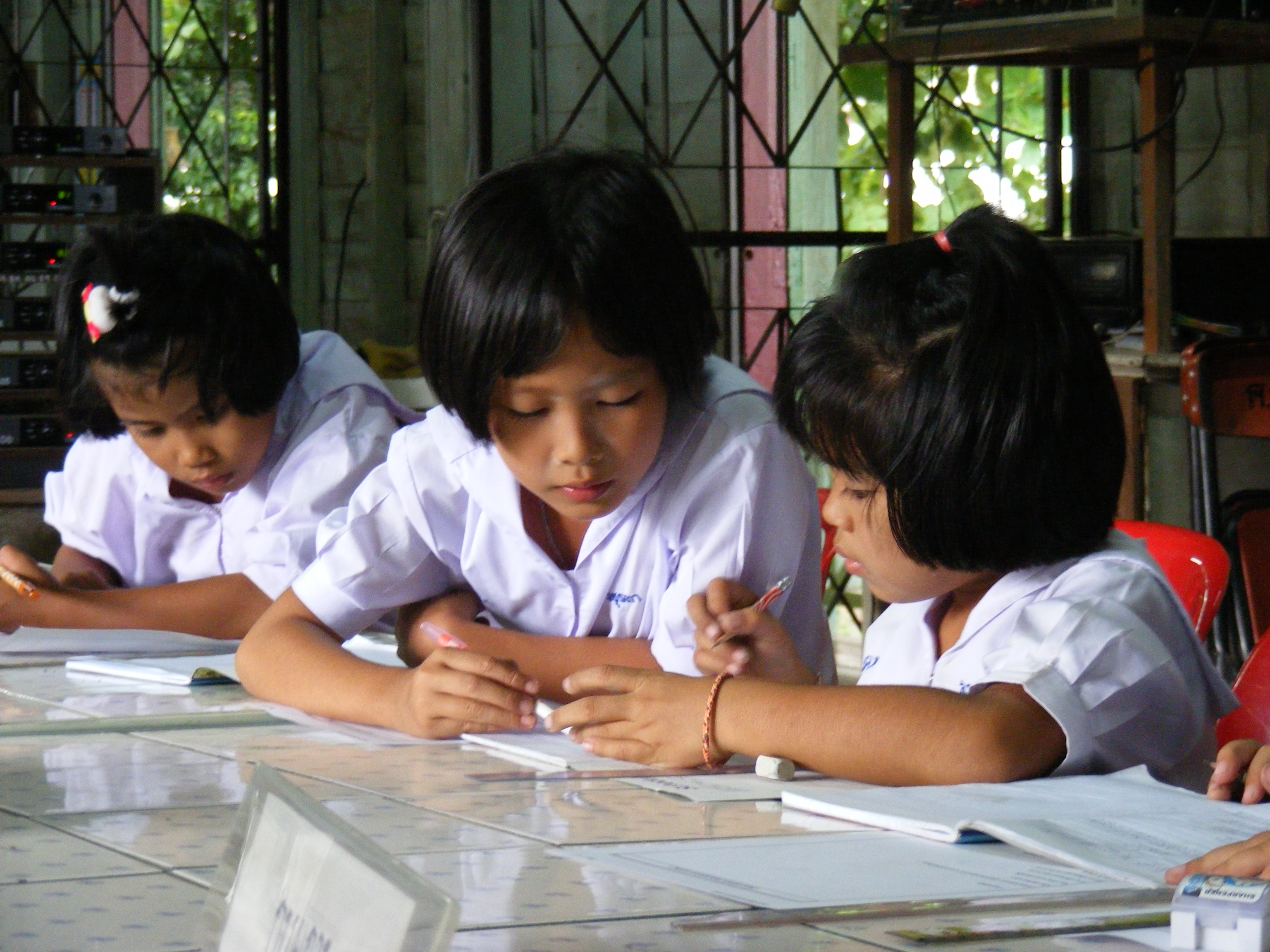 Thai pupils learning together at a classroom table in Uttaradit, Thailand
